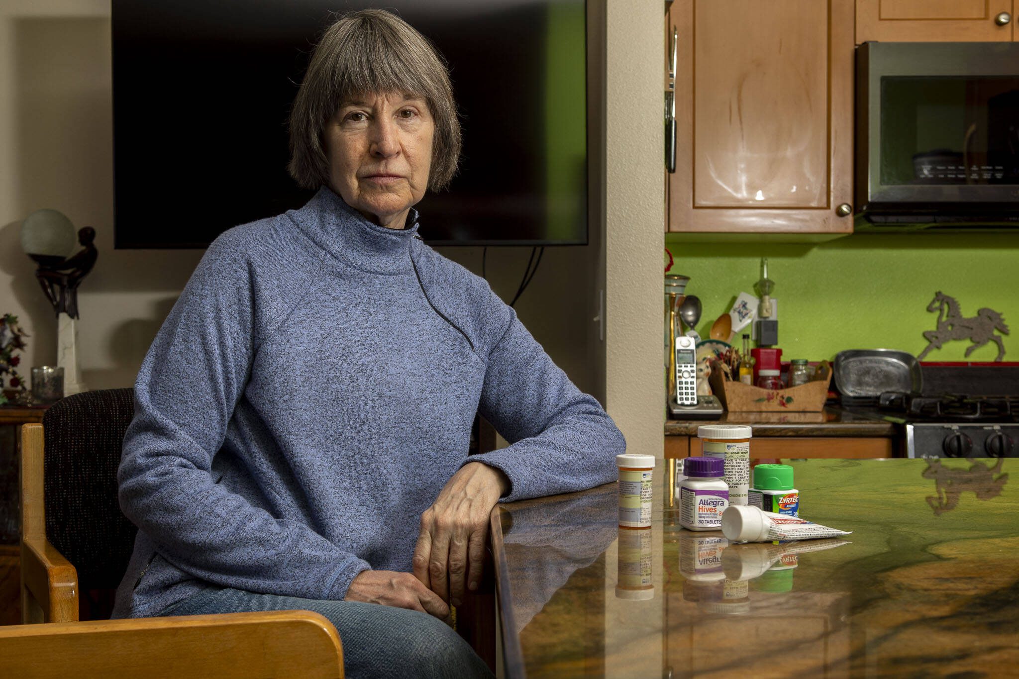 Cindy Clark, a Long-COVID patient, poses for a photo in her home with the various treatments she used in Mukilteo, Washington on Wednesday, Jan. 3, 2024. (Annie Barker / The Herald)