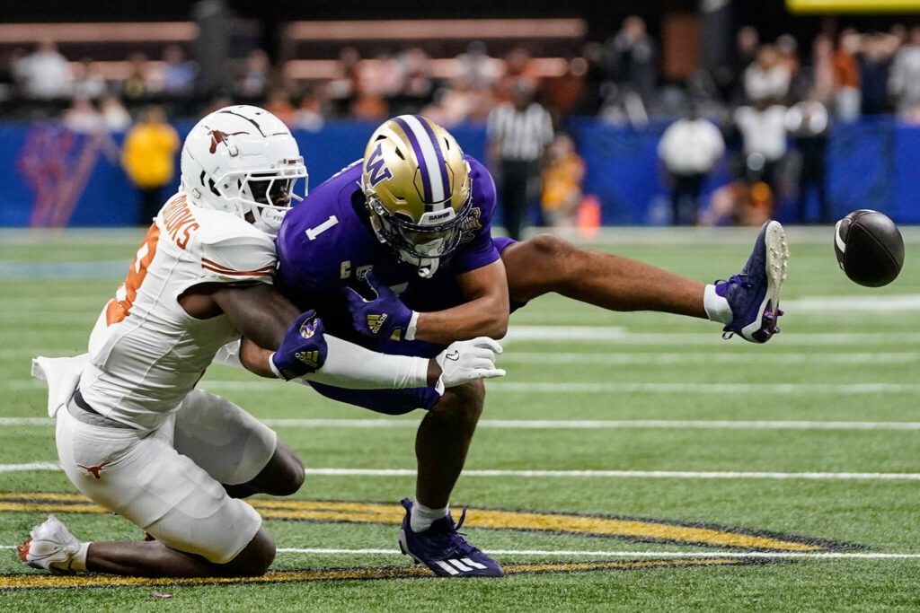 Texas defensive back Terrance Brooks (8) hits Washington wide receiver Rome Odunze (1) during the second half of the Sugar Bowl CFP NCAA semifinal college football game, Monday, Jan. 1, 2024, in New Orleans. Brooks received a interference penalty on the play. (AP Photo/Gerald Herbert)
