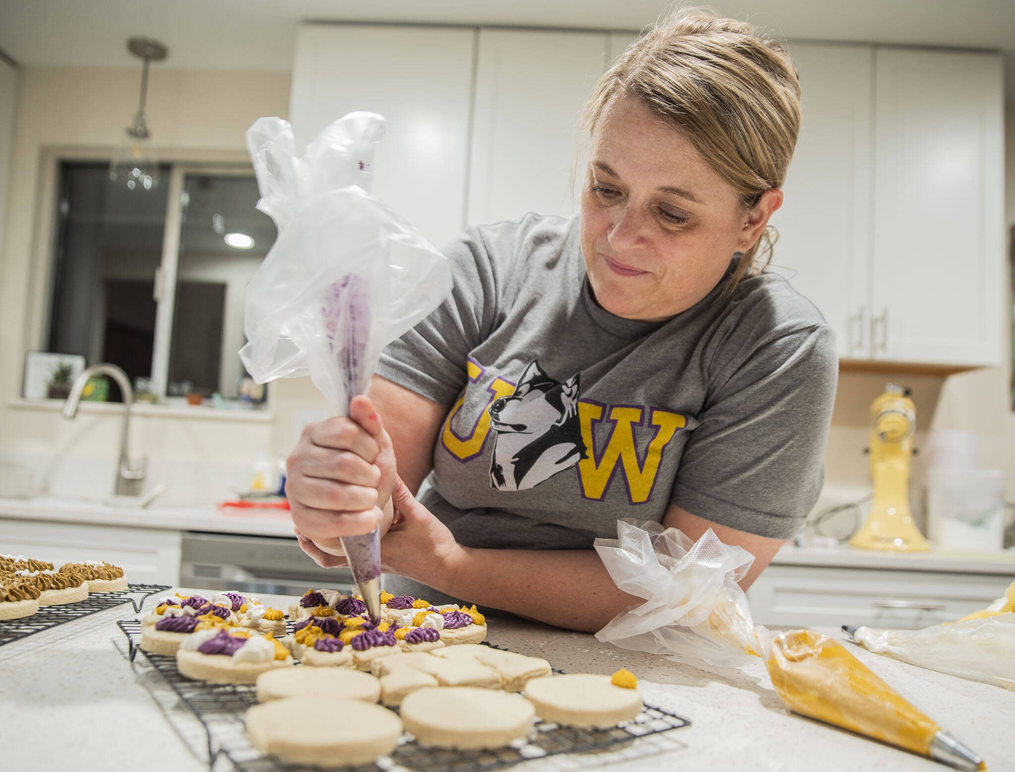 Andrea Ancich frosts University of Washington themed cookies at her Marysville home for her flight to the College Football Playoff National Championship in Texas. (Olivia Vanni / The Herald)