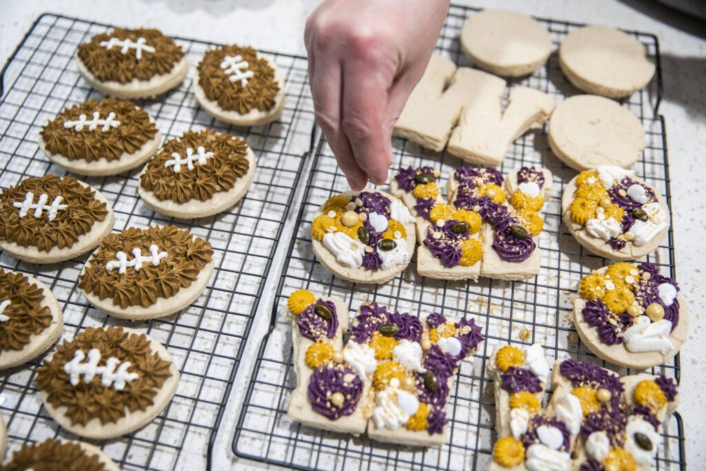 Andrea Ancich puts sprinkles on her University of Washington themed cookies. (Olivia Vanni / The Herald)
