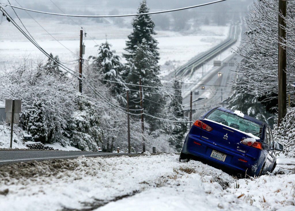 The driver of this car obviously ended up in the ditch while attempting to get down steep Cavalero Hill on 20th St. East in Everett, earlier Monday. Slippery conditions will likely continue late Monday and early Tuesday with freezing overnight temperatures. (Dan Bates / The Herald)
