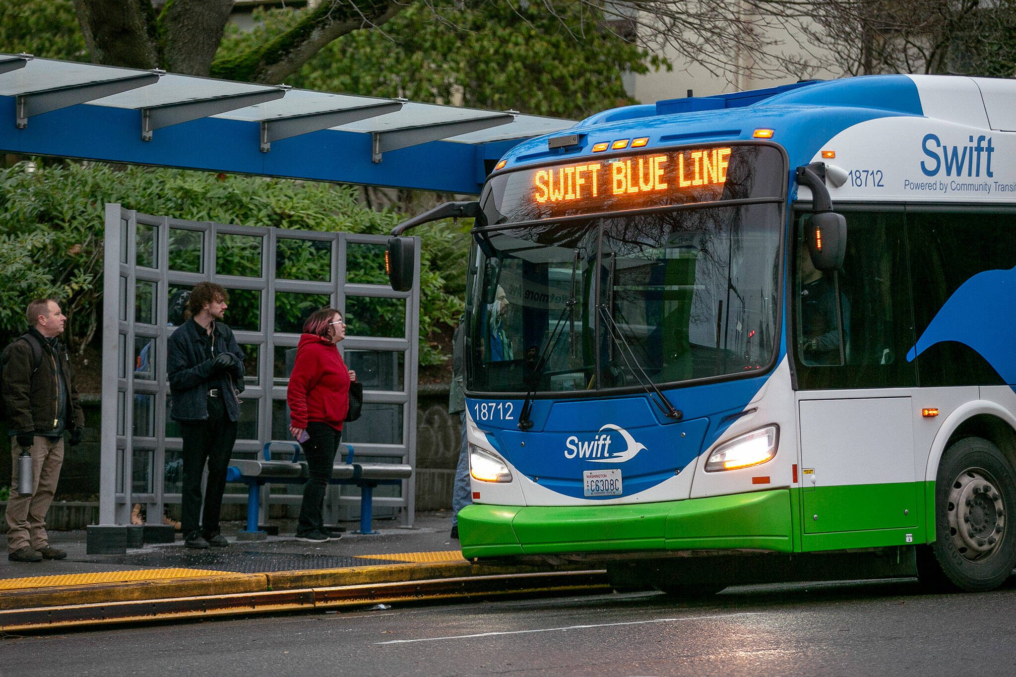 Riders wait to board as a southbound Swift Blue Line bus arrives at the stop on Pacific Avenue on Thursday, Jan. 11, 2024, in Everett, Washington. (Ryan Berry / The Herald)