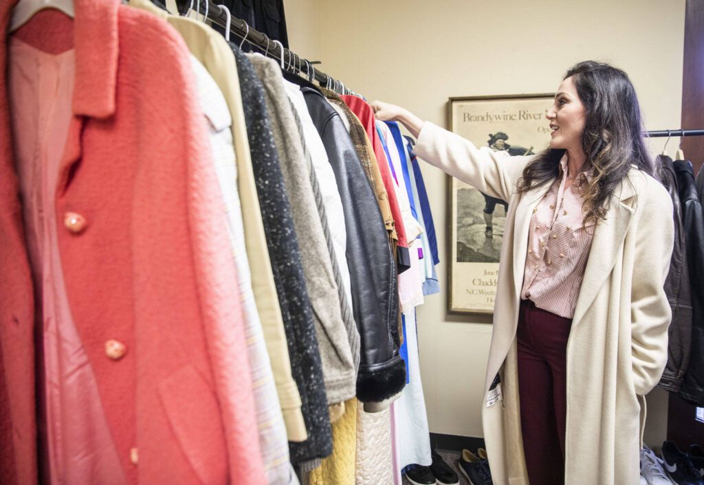 Kara Langus flips through her jackets available at Melrose and Vine Collective on Friday, Jan. 5, 2024 in Everett, Washington. (Olivia Vanni / The Herald)
