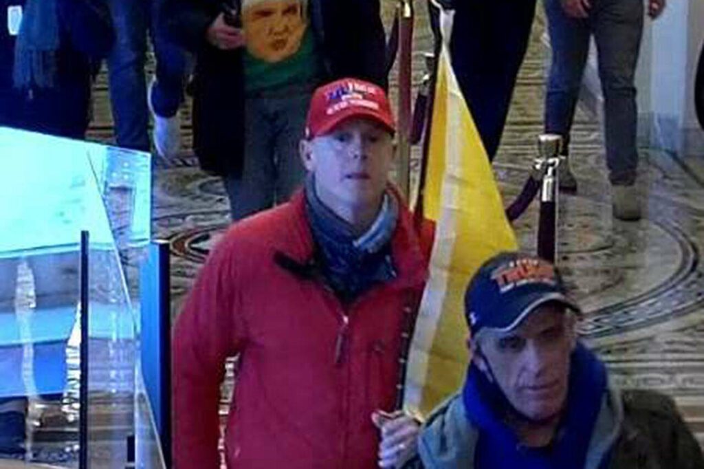Joseph Elliott Zlab is shown in video footage inside the U.S. Capitol building on Jan. 6, 2021, while wearing a red baseball cap and a red jacket, holding a yellow “Don’t Tread On Me” flag. (U.S. Attorney’s Office for the District of Columbia)
