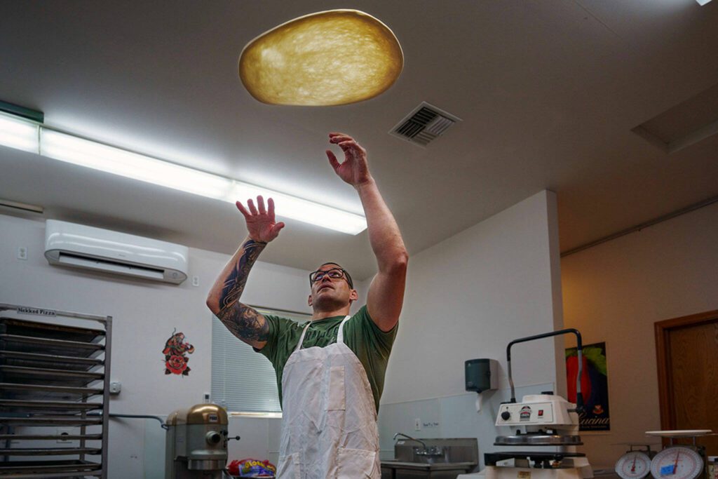 Paul Sarkis throws some pizza dough up in the air. (Photo by David Welton)
