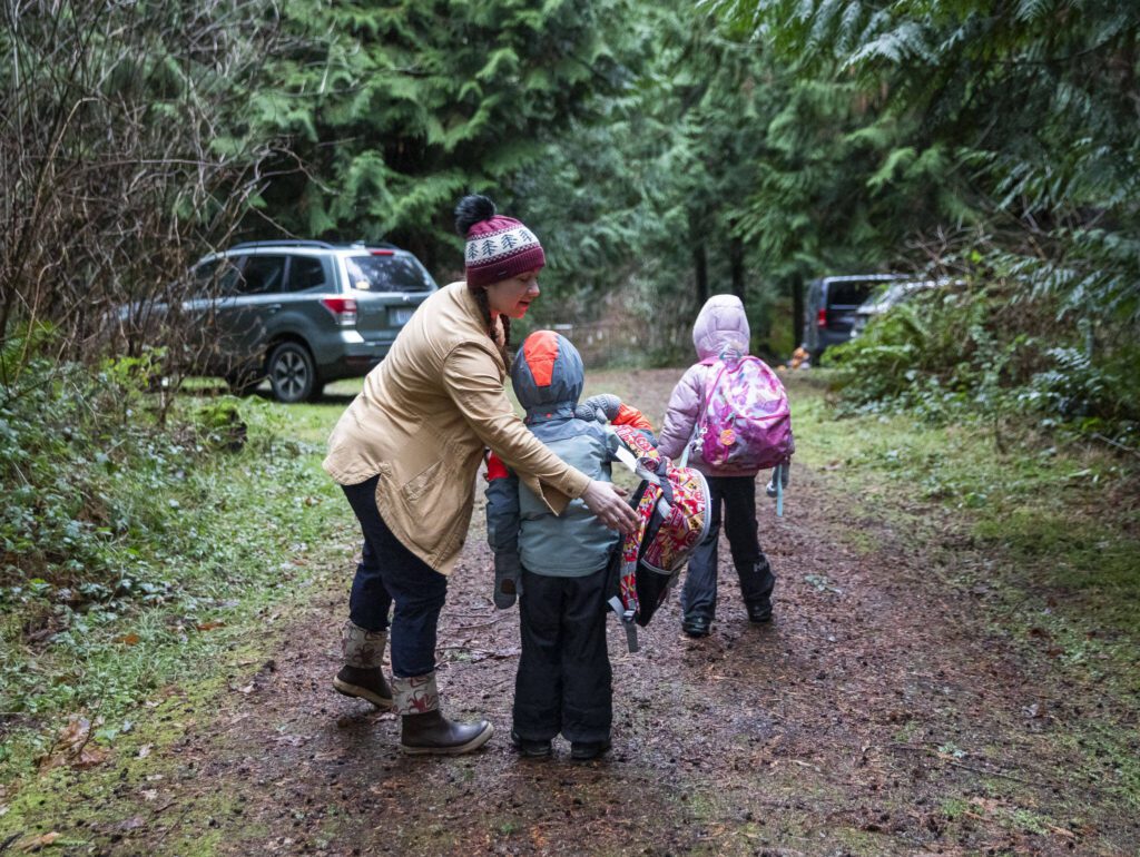 Heather White, co-founder of Springwood Forest School, helps a student put on their backpack on Monday, Jan. 22, 2024 in Camano Island, Washington. (Olivia Vanni / The Herald)

