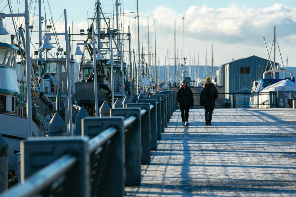 Beth Ross and Brittany Menzies walk along a frozen boardwalk at the Port of Everett on a chilly afternoon Friday, Jan. 12, 2024, in Everett, Washington. (Ryan Berry / The Herald)
