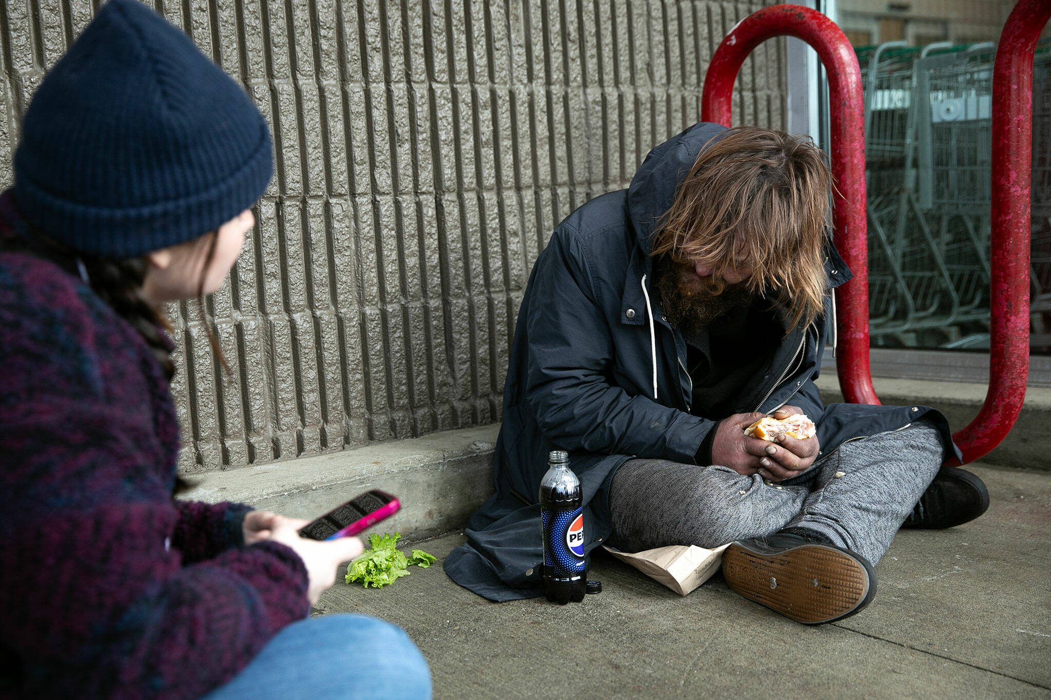 Liz Skinner of Domestic Violence Services of Snohomish County speaks with a man outside the Silver Lake Fred Meyer while conducting a point-in-time count Tuesday, Jan. 23, 2024, in Everett, Washington. PIT count volunteers scattered across the county to locate and survey unhoused people and collect data on the community. People in need were provided with some food and warming kits regardless of their participation in the count. (Ryan Berry / The Herald)