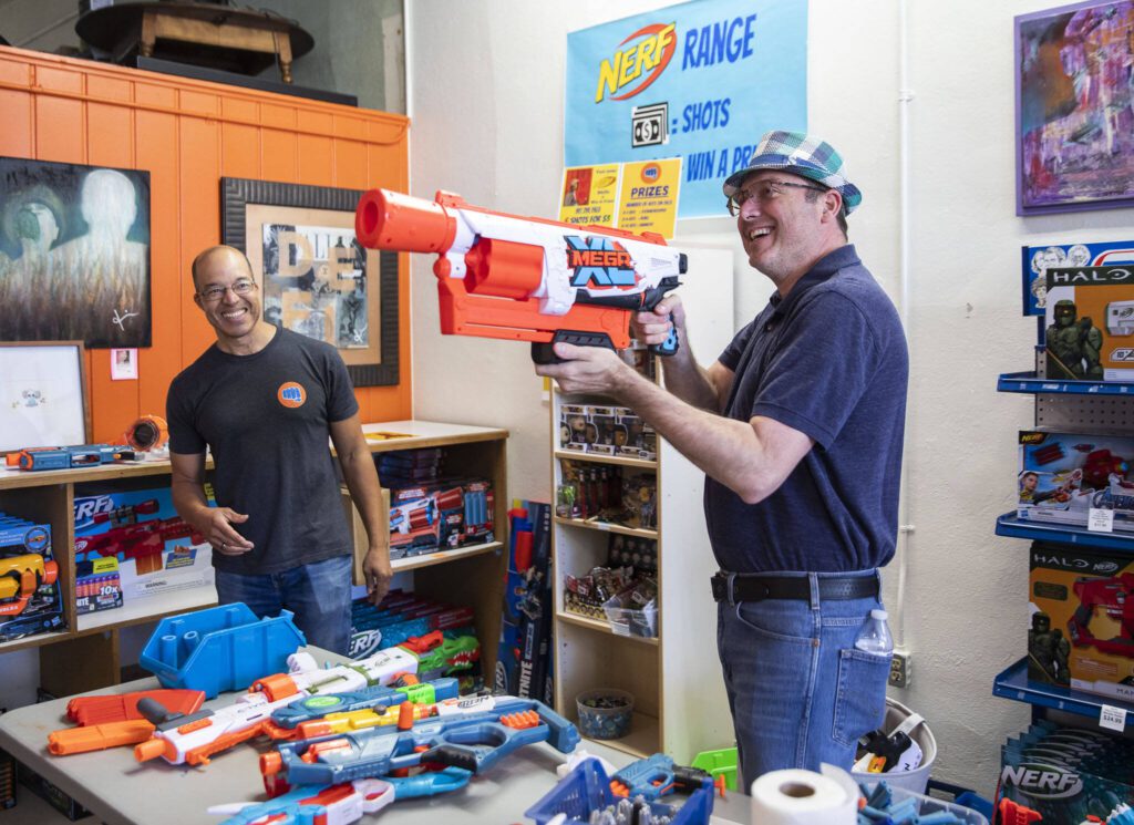 Tom Harrison laughs with a customer as they use the Nerf Range at his store on Tuesday, Sept. 6, 2022 in Everett, Washington. (Olivia Vanni / The Herald)
