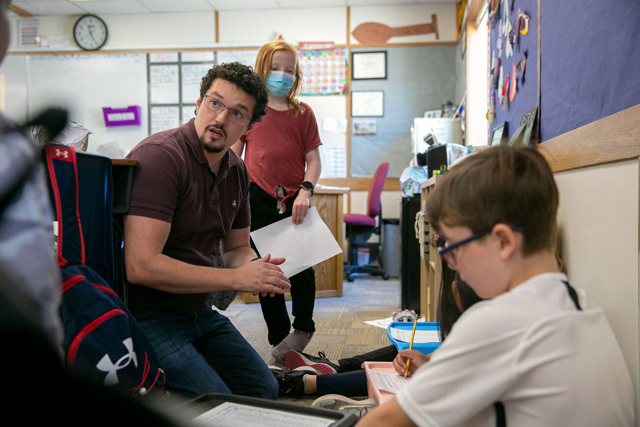 Zachary Pfrimmer gets together with a group of students to help them through an assignment in his fourth-grade classroom at Cedarhome Elementary on Wednesday, Sep. 21, 2022, in Stanwood, Washington. (Ryan Berry / The Herald)
