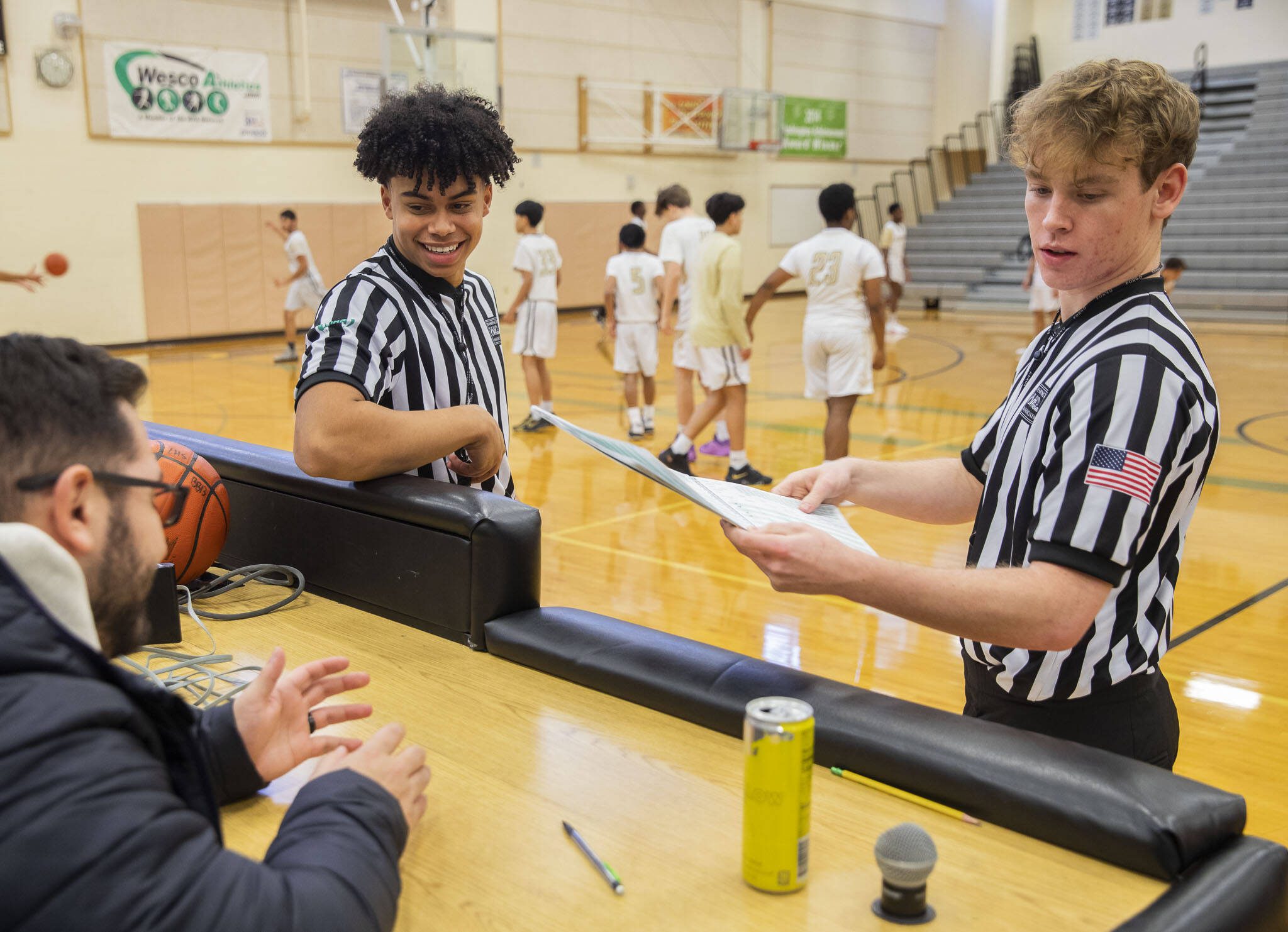 Mountlake Terrace students and referees Chandler Hyde, left, and Matthew Meadows, right, get ready before the start of a basketball game Jan. 16 at Lynnwood High School in Bothell. (Olivia Vanni / The Herald)