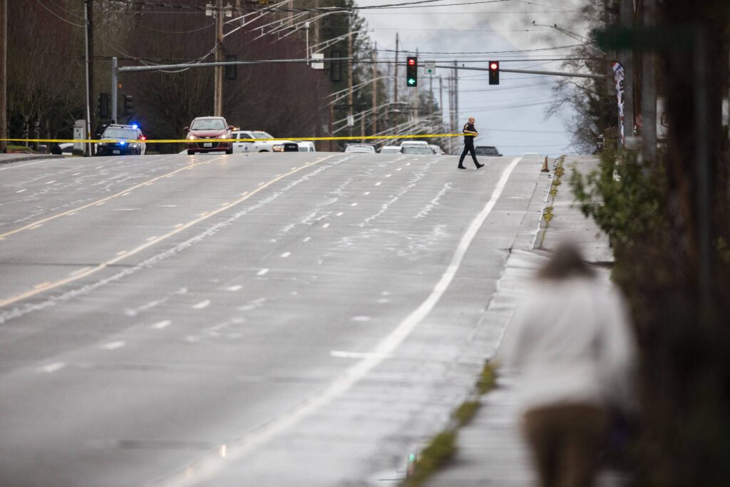 A police officer walks across 112th Street SW with police tape on Wednesday, Jan. 31, 2024 in Everett, Washington. (Olivia Vanni / The Herald)
