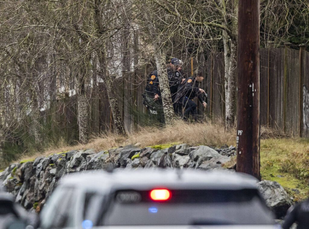 Police officers break a hole in a fence along 112th Street SW on Wednesday, Jan. 31, 2024 in Everett, Washington. (Olivia Vanni / The Herald) 
