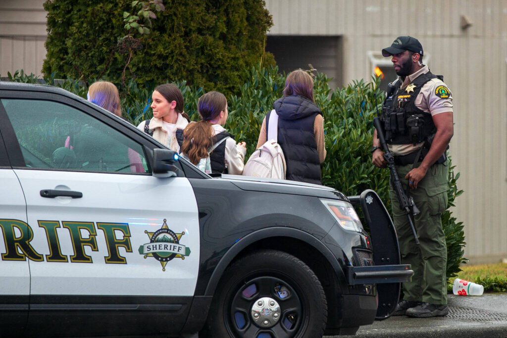 A Snohomish County sheriff’s deputy speaks to a group of young girls trying to go home from school during a police standoff Wednesday, Jan. 31, 2024, in south Everett, Washington. (Ryan Berry / The Herald)
