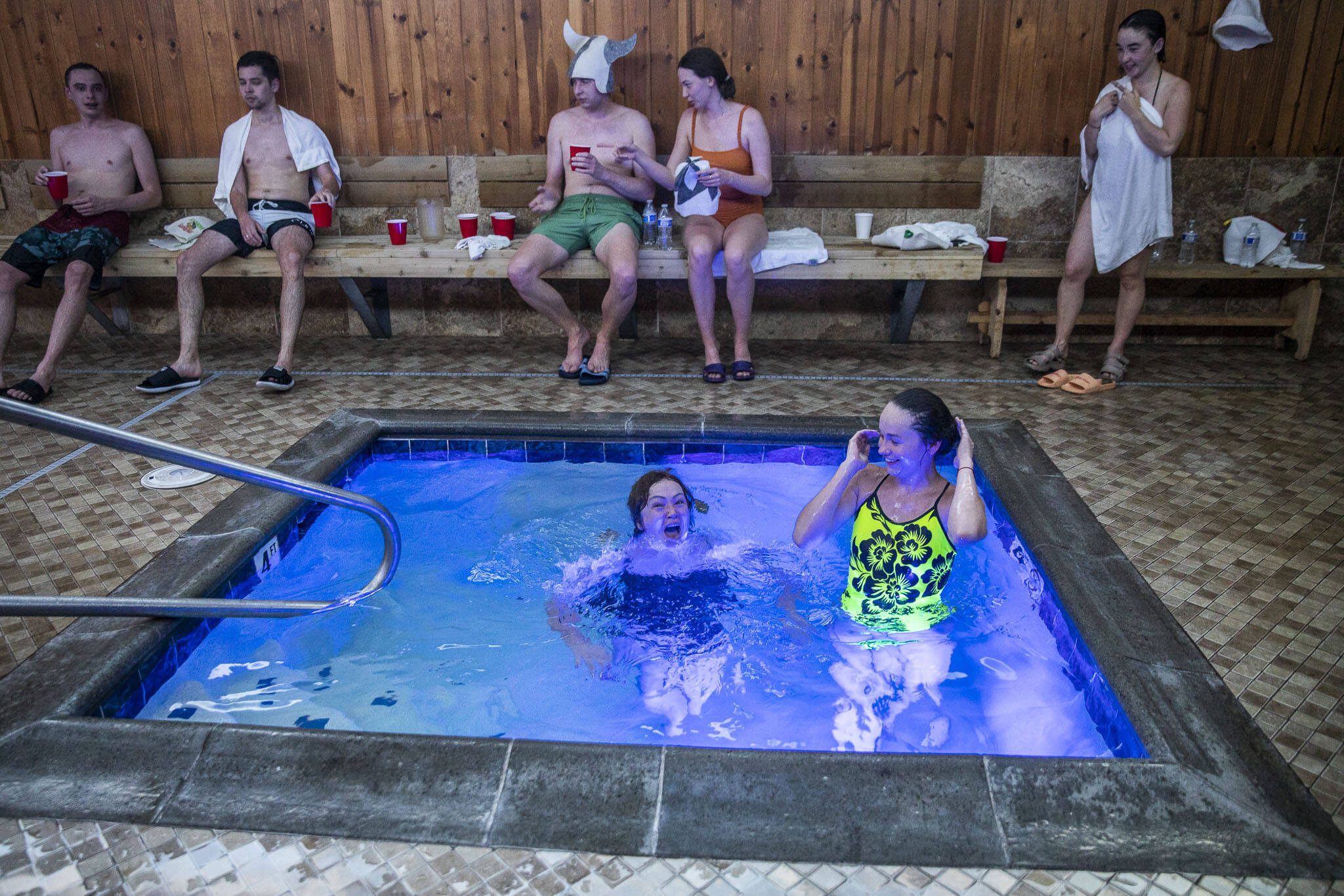 Nora Z., center, reacts while jumping into a cold pool after getting out of the hot sauna at Banya in Everett. (Olivia Vanni / The Herald)