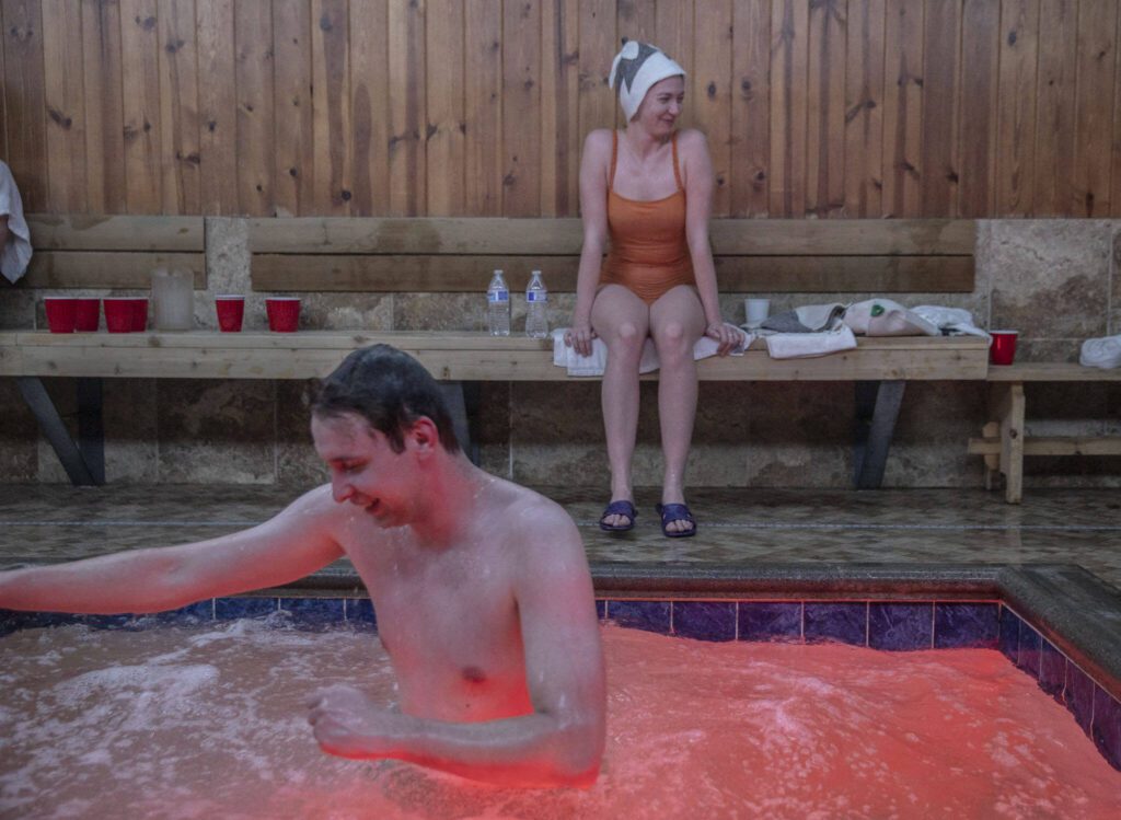Alex S., left, and Kate S., right, hang out in a pool area after getting out of the hot sauna at Banya in Everett. (Olivia Vanni / The Herald)

