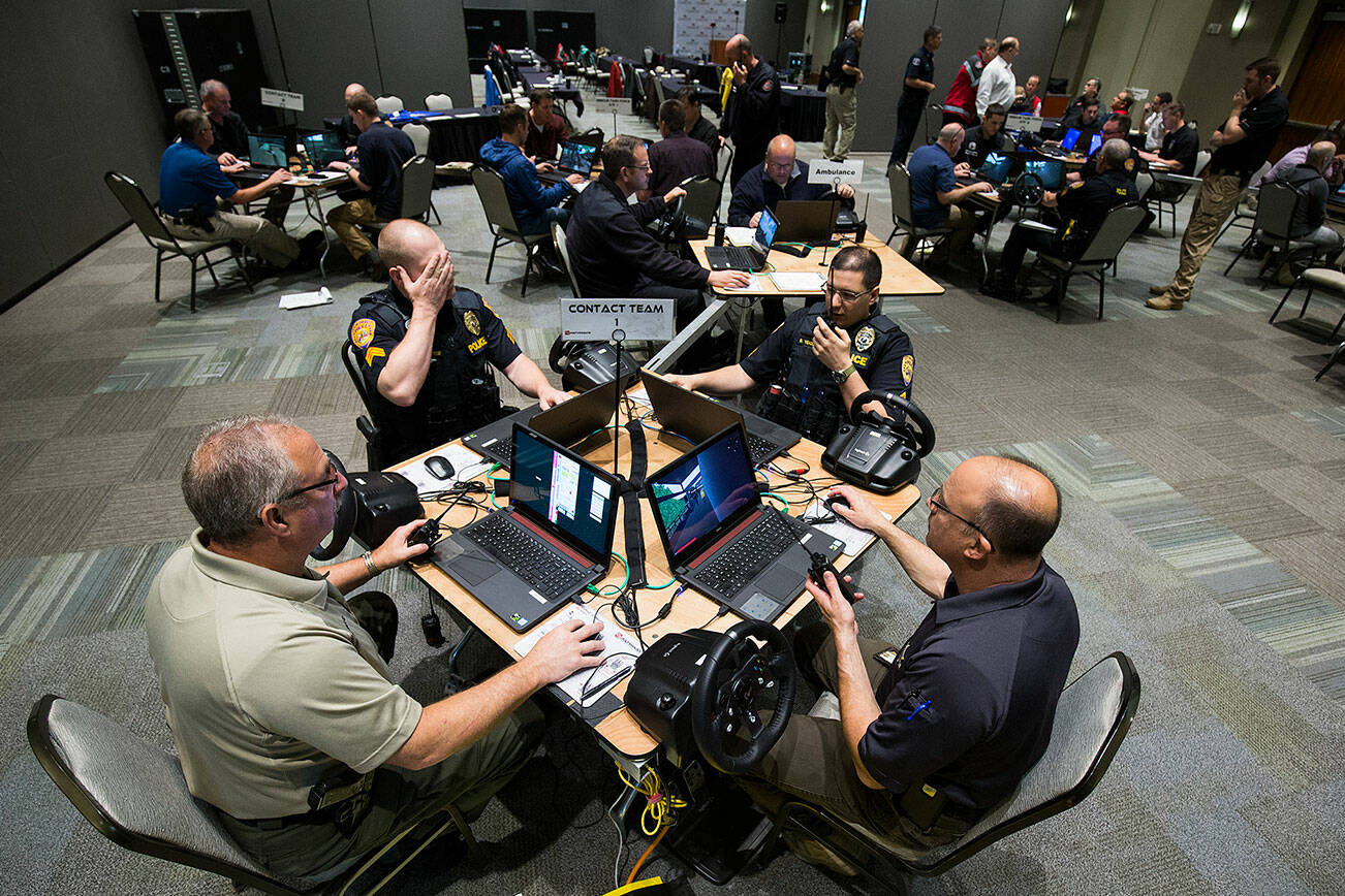 Law enforcement officers, firefighters and medics from Snohomish, King and Pierce counties use computers to simulate an active shooter scenario in a ballroom at Angel of the Winds Arena on Wednesday, June 13, 2018 in Everett, Wa. (Andy Bronson / The Herald)