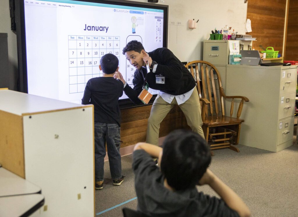 Student teacher Joshua Wisnubroto helps a Picnic Point Elementary student work on a calendar activity. (Olivia Vanni / The Herald)
