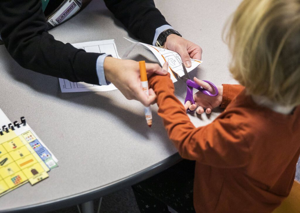 Student teacher Joshua Wisnubroto helps a student cut a piece of paper. (Olivia Vanni / The Herald)
