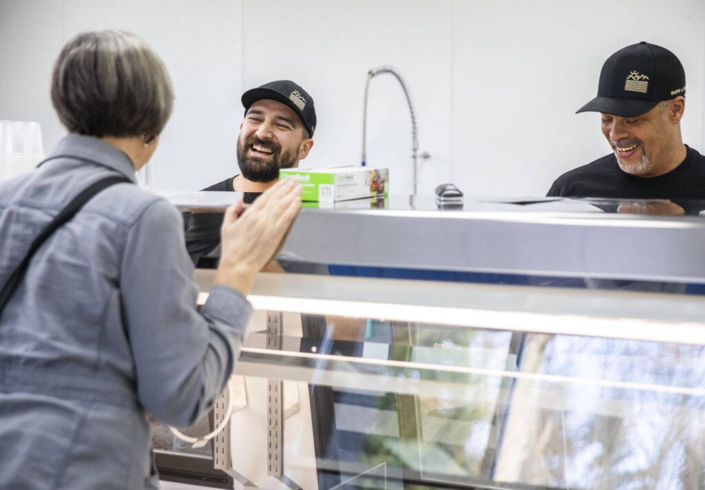 Earth and Ocean co-owners Chris Mills, left, and Fermin Lopez chat with a customer. (Olivia Vanni / The Herald)
