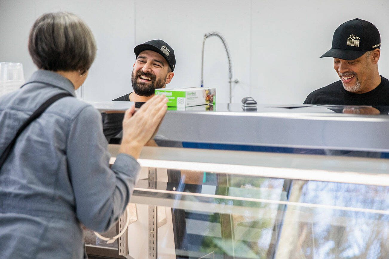 Chris Mills, left, and Fermin Lopez, right, smile and talk with a customer at Earth & Ocean on Tuesday, Jan. 23, 2024 in Mukilteo, Washington. (Olivia Vanni / The Herald)