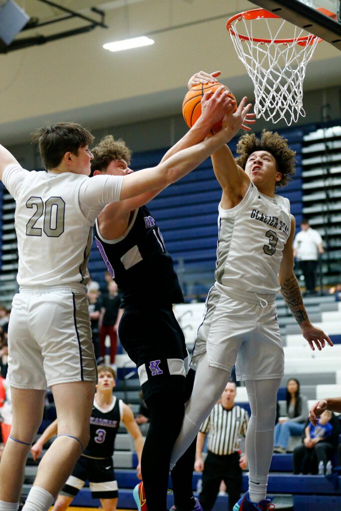 Glacier Peak’s Zachary Albright (20) and Isaiah Cuellar (3) fight Kamiak’s David Zieve for a rebound during a game on Thursday at Glacier Peak High School in Snohomish. (Ryan Berry / The Herald)
