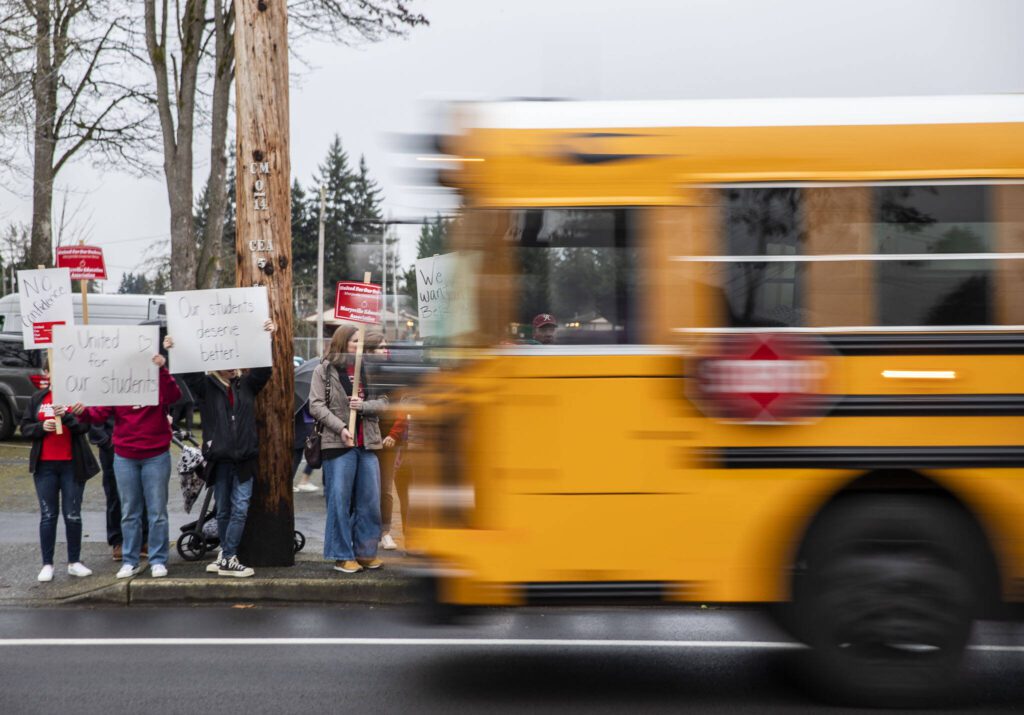 A school bus drives by rally before a Marysville School Board meeting on Monday, Feb. 5, 2024 in Marysville, Washington. (Olivia Vanni / The Herald)
