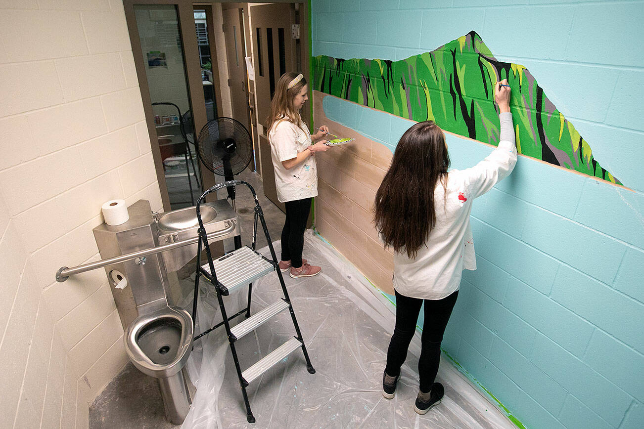 Cousins Penny Leslie and Sidney Baker work together on a mural inside a jail cell at the Mukilteo Police Department on Sunday, Feb. 18, 2024, in Mukilteo, Washington. (Ryan Berry / The Herald)