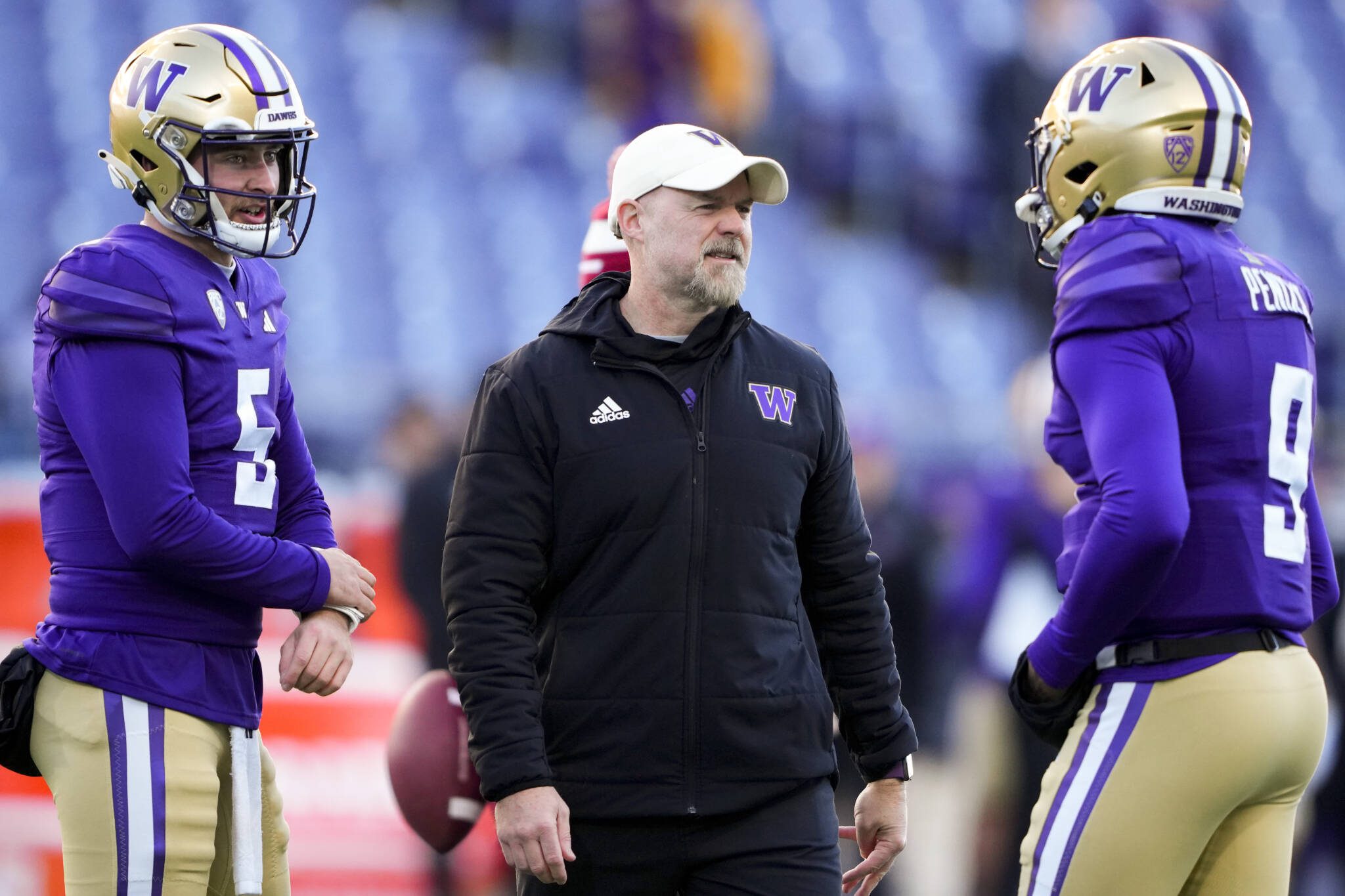 Former Washington offensive coordinator Ryan Grubb, center, talks with quarterback Dylan Morris (5) and quarterback Michael Penix Jr. (9) as they warm up before a game Nov. 25, 2023, in Seattle. Grubb is expected to be the next offensive coordinator of the Seattle Seahawks. (AP Photo/Lindsey Wasson)
