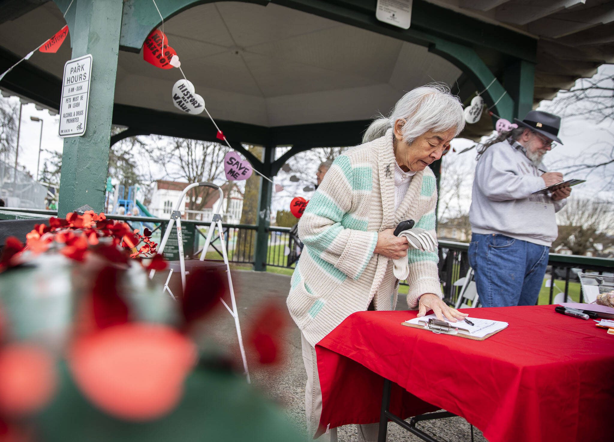 Lyla Anderson and others sign a petition to save the Clark Park gazebo during a “heart bomb” event hosted by Historic Everett on Saturday, Feb. 17, 2024 in Everett, Washington. (Olivia Vanni / The Herald)