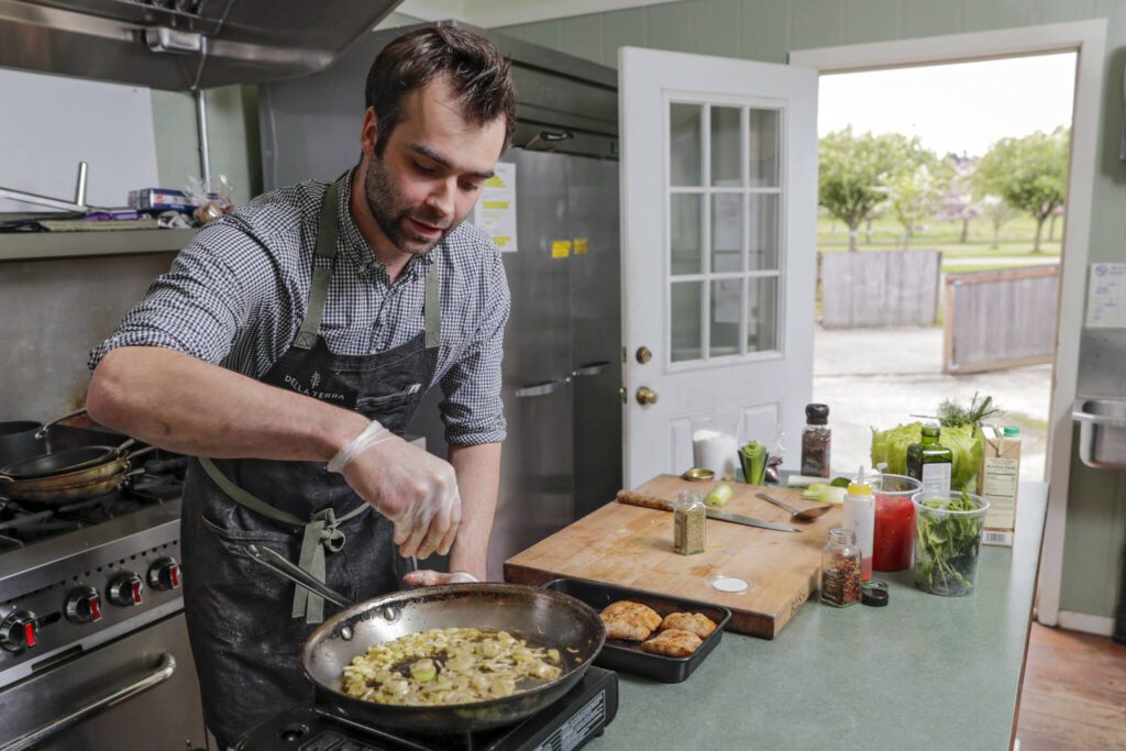 Chef Cody Castiglia of Della Terra, a catering company in Snohomish, prepares a dish of Black Cod Acqua Pazza. (Kevin Clark / The Herald)
