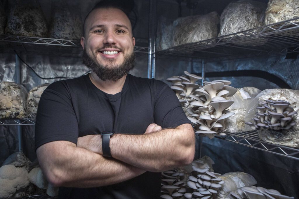 Nathanael Engen poses for a photo with mushrooms he grows at his property in Everett, Washington on Monday, March 27, 2023. Engen describes his business as “cultivating mushrooms, and healthy communities.” (Annie Barker / The Herald)
