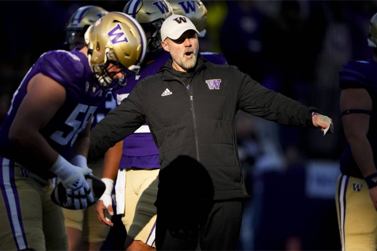 Washington offensive coordinator Ryan Grubb stands on the field as players warm up before facing Washington State in an NCAA college football game Saturday, Nov. 25, 2023, in Seattle. (AP Photo/Lindsey Wasson)