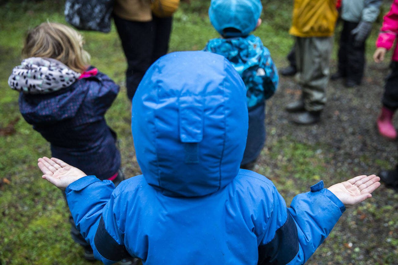 A student reaches put their hands to feel raindrops as it begins to pour on Monday, Jan. 22, 2024 in Camano Island, Washington. (Olivia Vanni / The Herald)