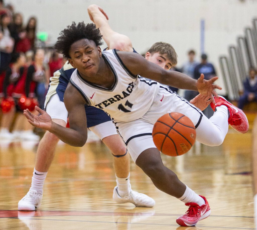 Mountlake Terrace’s Rayshaun Connor is tripped up by Arlington’s Leyton Martin while taking the ball down the court during the 3A boys district championship game on Saturday, Feb. 17, 2024 in Marysville, Washington. (Olivia Vanni / The Herald)

