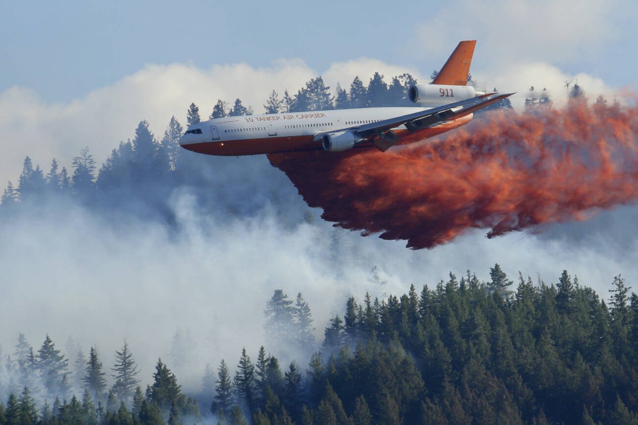 FILE - In this Aug. 21, 2015 file photo, a tanker airplane drops fire retardant on a wildfire burning near Twisp, Wash. Three firefighters were killed battling the blaze. The story was a top Washington state news item in 2015. Public Lands Commissioner Hilary Franz has proposed a plan to strengthen the ways that Washington can prevent and respond to wildfires. Franz released the 10-year plan last week as part of her $55 million budget request to the Legislature to improve the state's firefighting abilities (AP Photo/Ted S. Warren, File)
