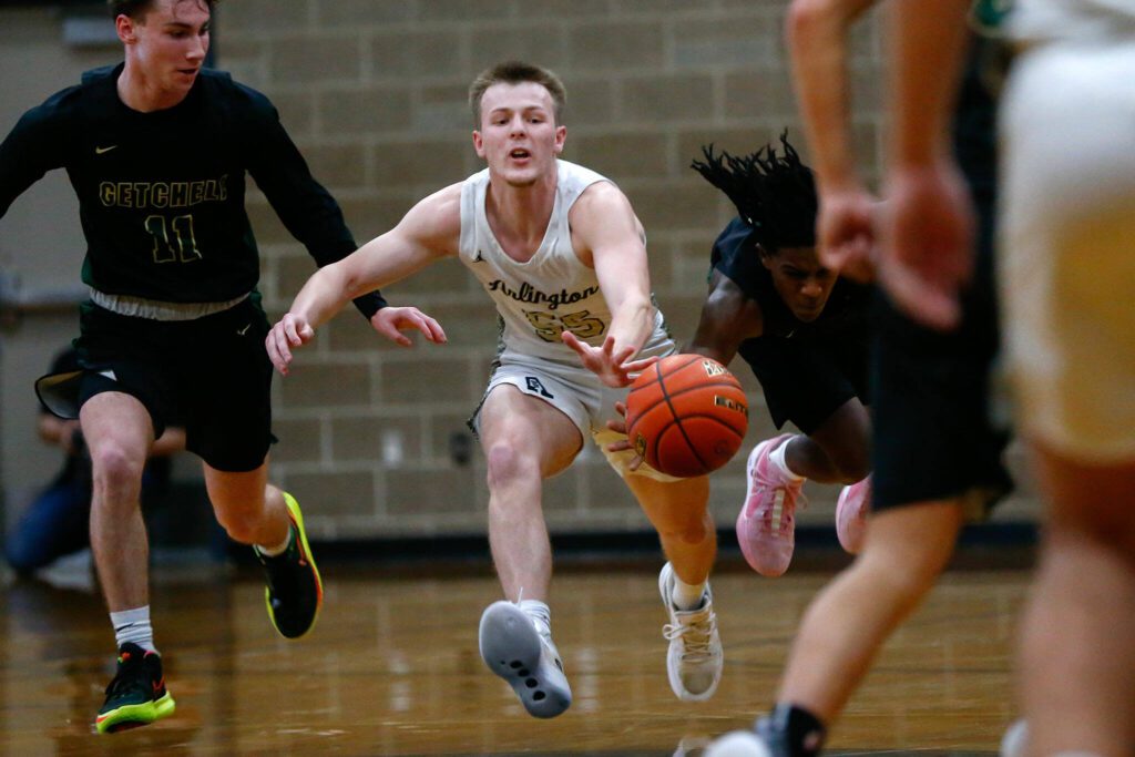 Arlington’s Jackson Trotter is fouled from behind while trying to advance the ball against Marysville Getchell during a playoff matchup at Arlington High School on Saturday, Feb. 24, 2024, in Arlington, Washington. (Ryan Berry / The Herald)
