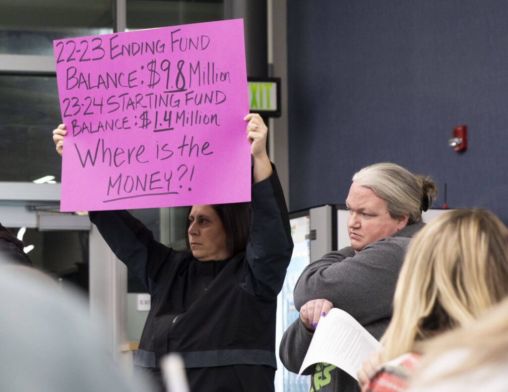 Jalleh Hooman holds up a sign in protest at the Marysville School District budget presentation on Tuesday, Nov. 28, 2023 in Marysville, Washington. (Olivia Vanni / The Herald)
