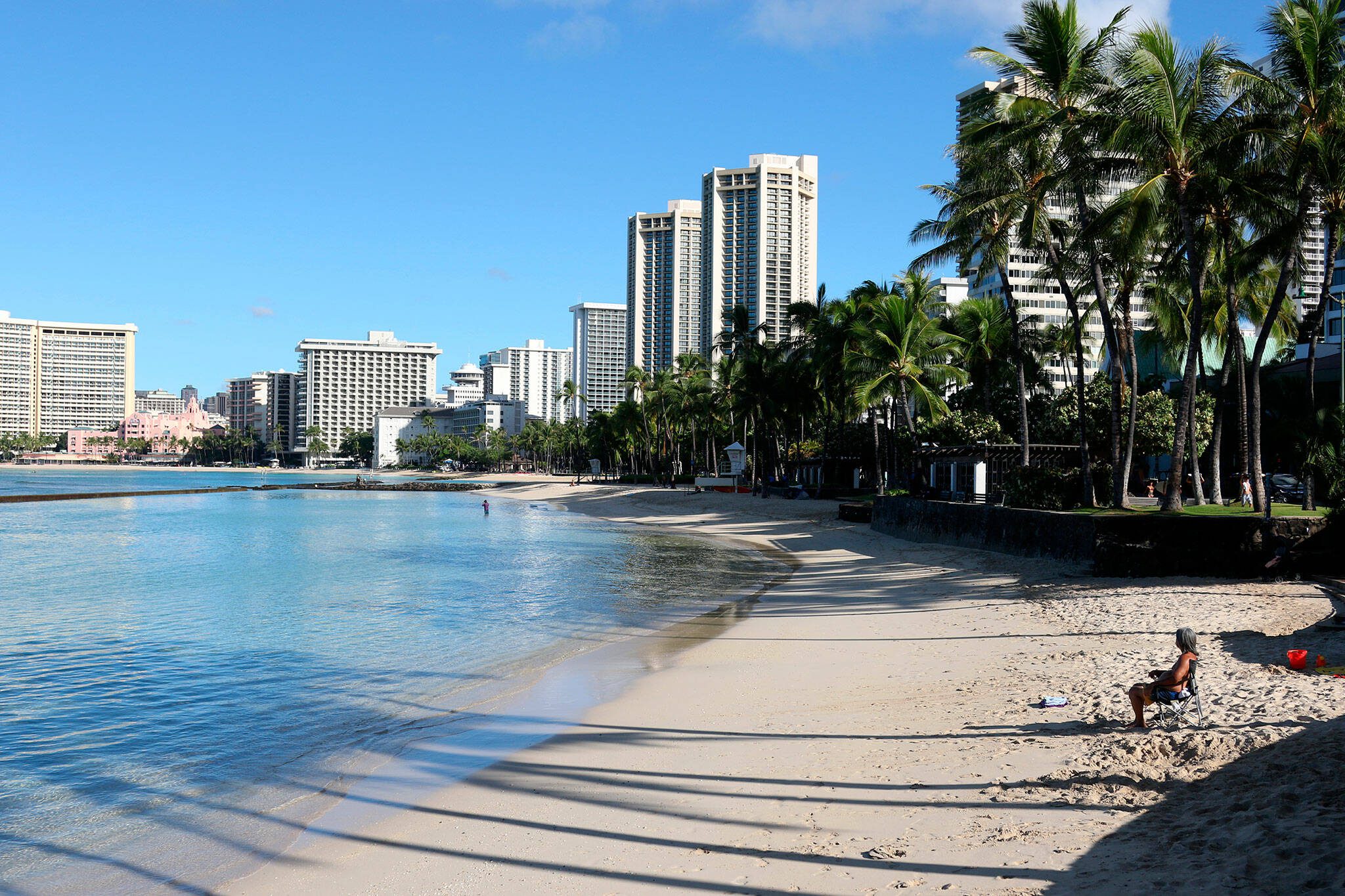 A man sits on a nearly empty Waikiki Beach in Honolulu, Friday, Oct. 2, 2020. (AP Photo/Caleb Jones, file)