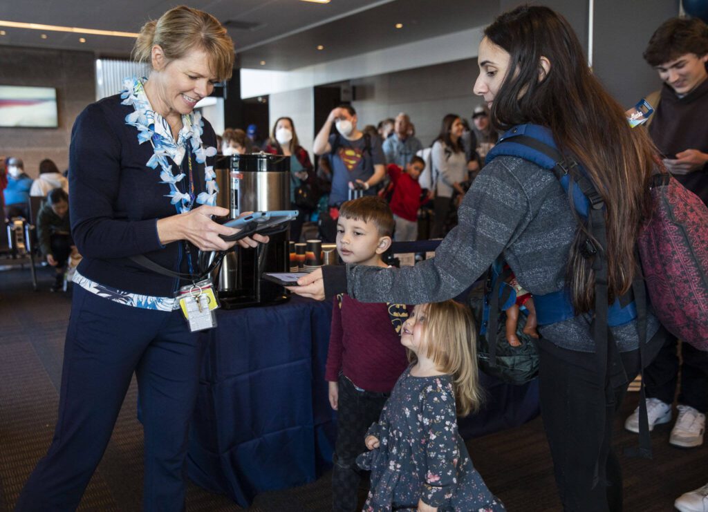 Katie Wallace, left, checks people into the first flight from Paine Field to Honolulu on Nov. 17, 2023 in Everett. (Olivia Vanni / The Herald)
