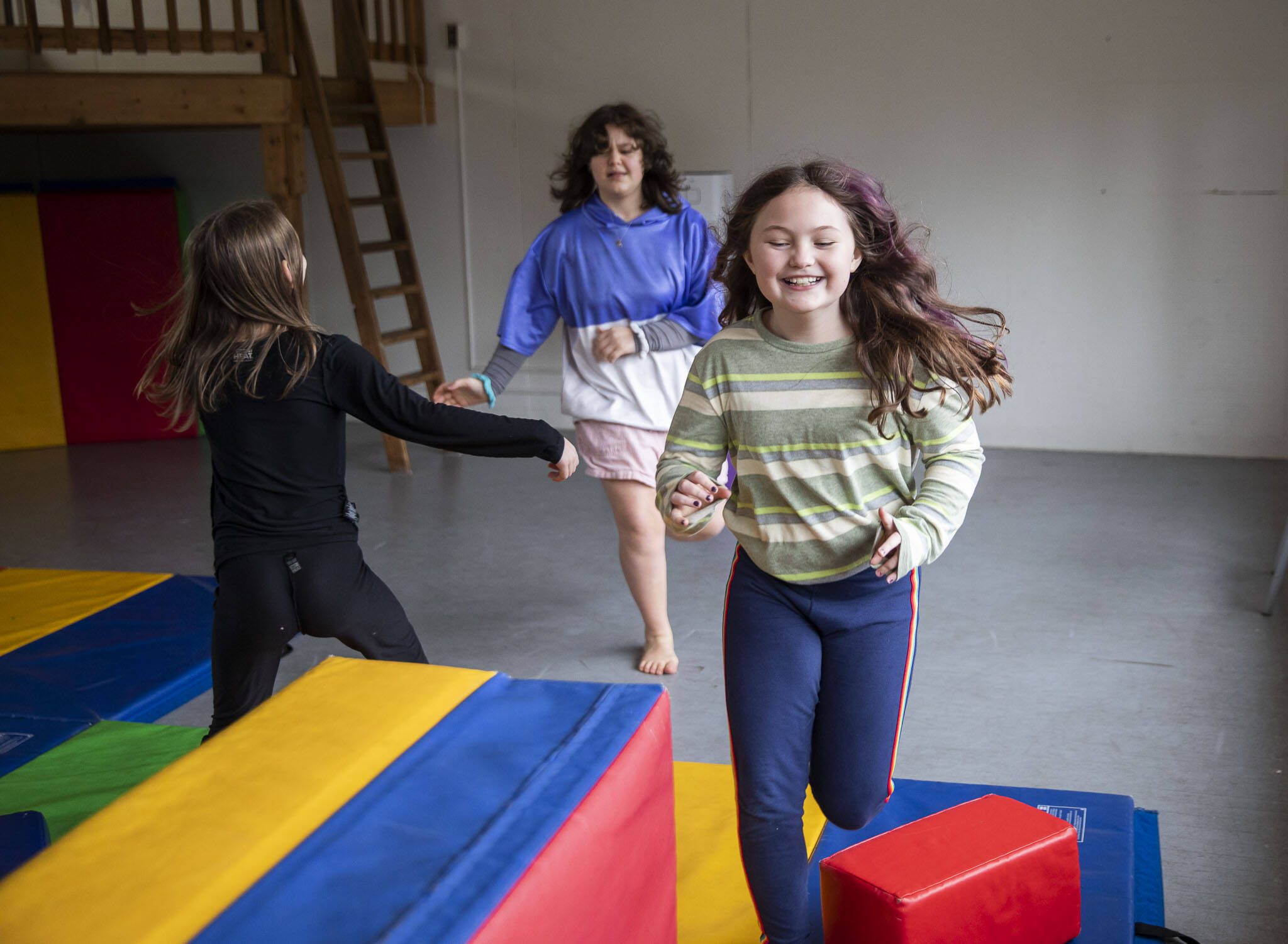 Madi Humpries, 9, right, Rose Austin, 13, center, and Eirene Ritting, 8, runs around a large open activity room at Clearwater School on Thursday, Jan. 25, 2024 in Bothell, Washington. (Olivia Vanni / The Herald)