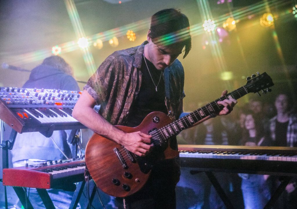 Owen Mayo of Cytrus picks up his guitar to play during a headlining show at Madame Lou’s on Friday, Dec. 29, 2023 in Seattle, Washington. (Olivia Vanni / The Herald)
