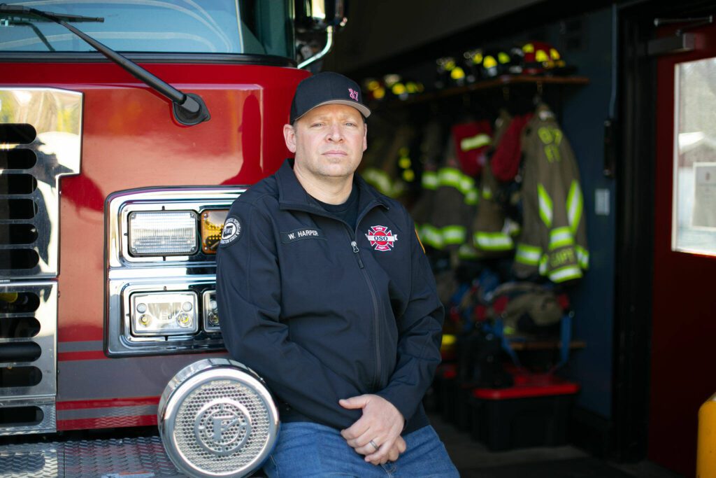 Oso Fire Chief Willy Harper sits on the bumper of a fire engine at the Oso Fire Station on Friday, March 15, 2024, in Oso, Washington. Harper was chief of the department at the time of the slide ten years ago. (Ryan Berry / The Herald)
