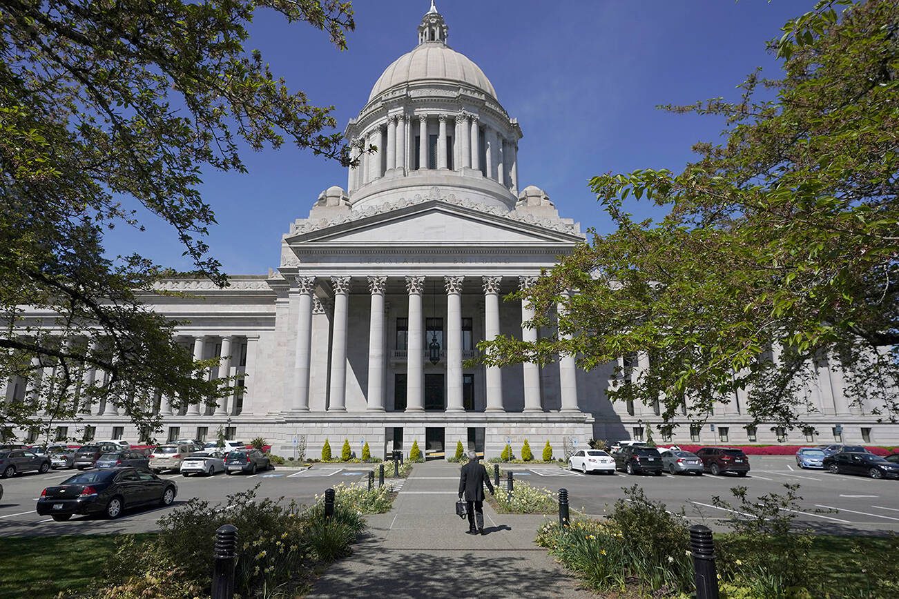 FILE - A person walks near the Legislative Building, Wednesday, April 21, 2021, at the Capitol in Olympia, Wash. Washington's redistricting commission failed to meet its deadline and on Tuesday, Nov. 16, kicked the job of creating new political maps to the state Supreme Court. The bipartisan commission had a deadline of 11:59 p.m. Monday to approve new boundaries for congressional and legislative districts following the 2020 census. (AP Photo/Ted S. Warren, File)