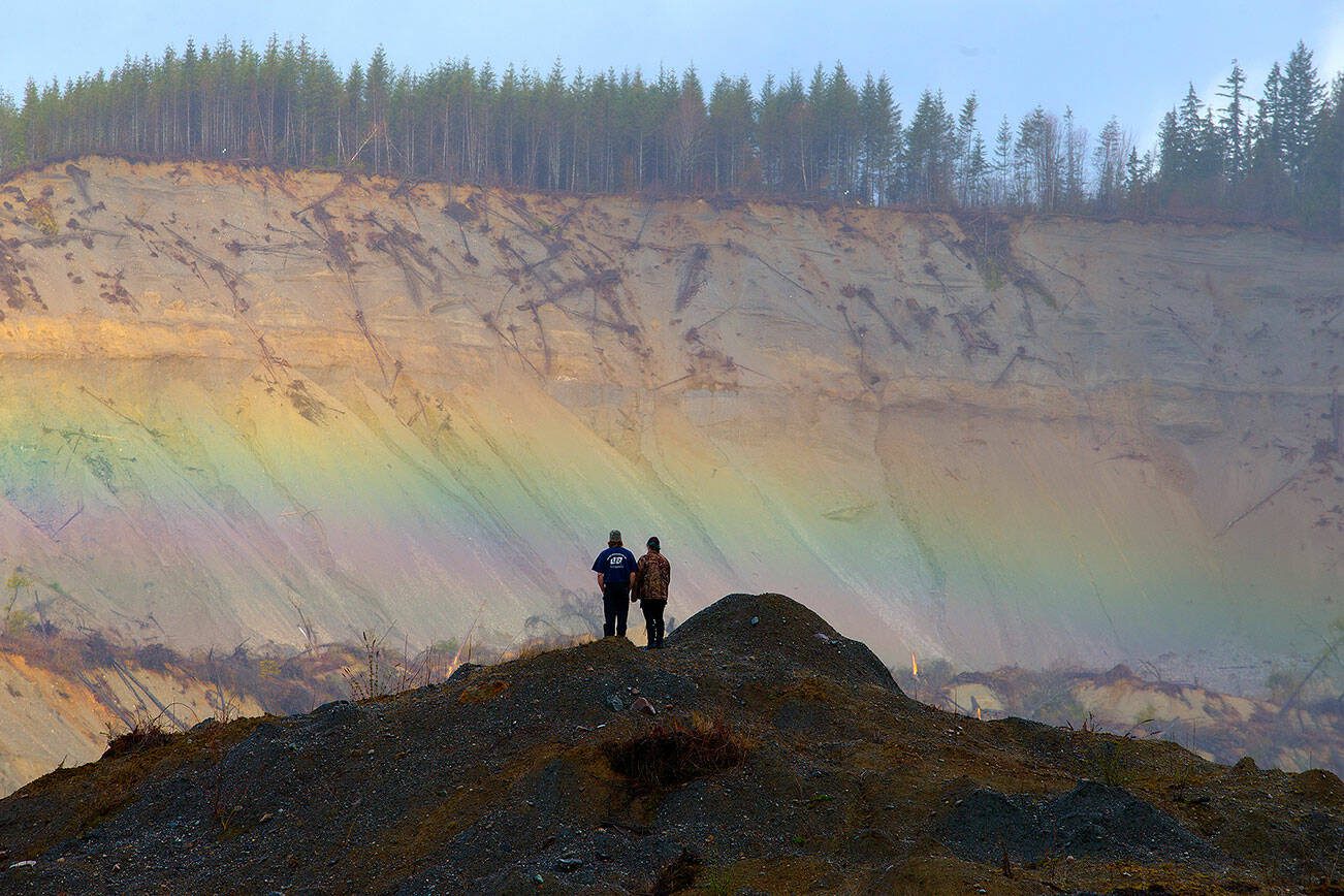 A rainbow appears in front of Andy Huestis and his girlfriend Alisha Garvin as they and other families gather to remember the victims on the third anniversary of the Oso mudslide on Wednesday, March 22, 2017 in Oso, Wa. Huestis' sister, Christina Jefferds, and her baby granddaughter, Sanoah Violet Huestis, were among the 43 people killed in the mudslide.  (Andy Bronson / The Herald)
