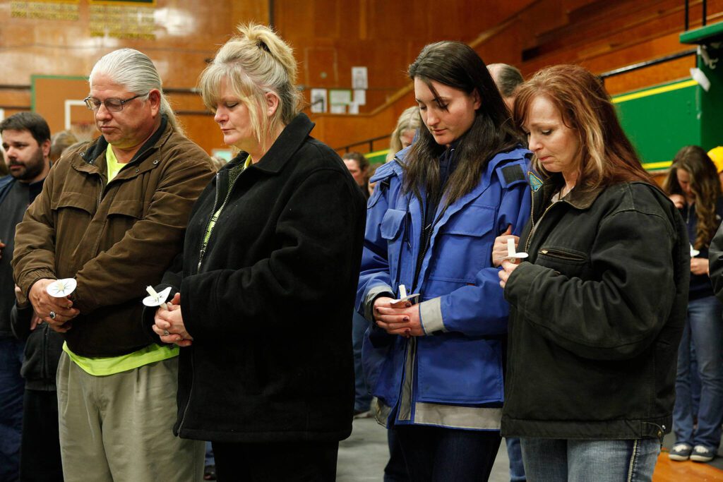 Tawnya Nettles, Gabby Kernaghan, and other community members (from right to left) pray during a candlelight vigil at the Darrington Community Center, Saturday, April 5, 2014, in Darrington, Wash. (Sofia Jaramillo / The Herald)
