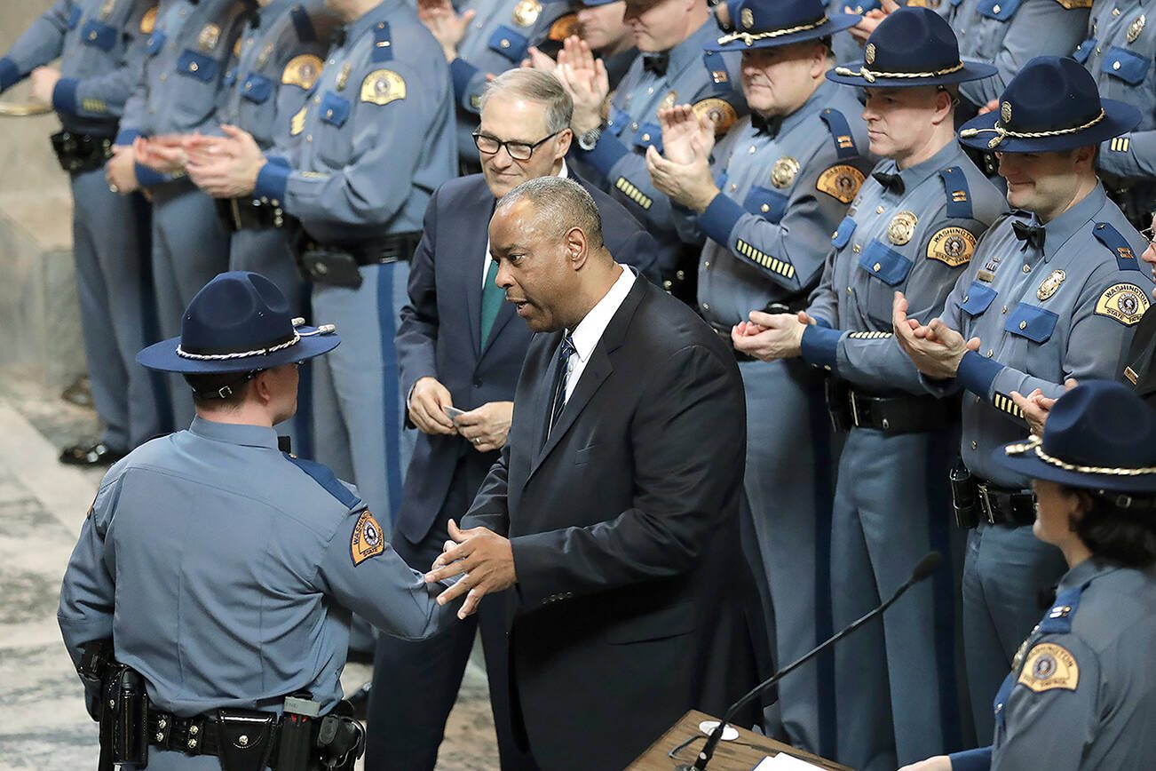 Washington State Patrol Chief John Batiste, center, greets a new trooper during a graduation ceremony, as Gov. Jay Inslee looks on in the Rotunda at the Capitol Thursday, Dec. 13, 2018, in Olympia, Wash. The class of 31 troopers completed more than 1,000 hours of training and will now work for the WSP across the state. (AP Photo/Ted S. Warren)