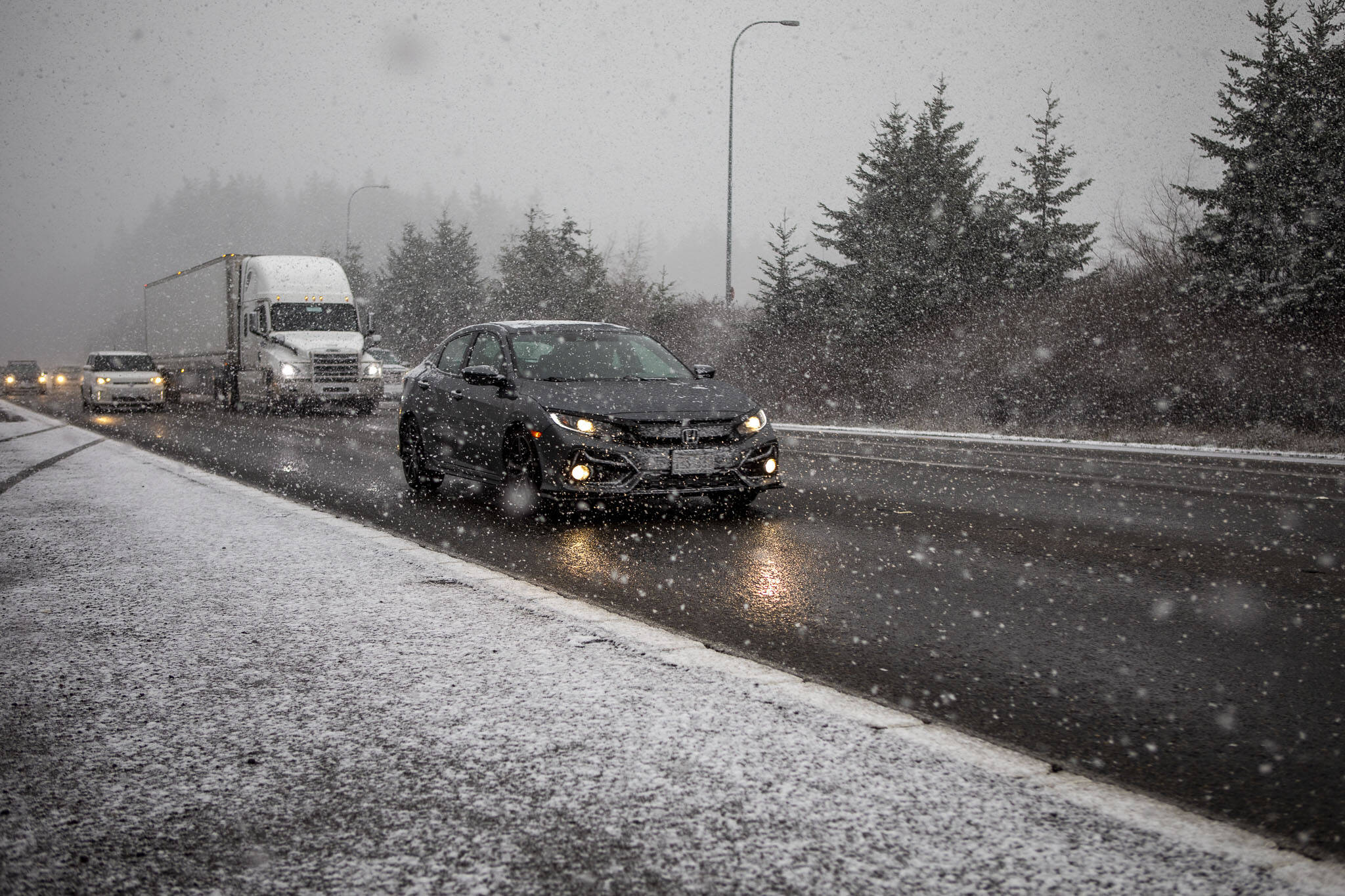 Cars drive through snow along I-5 in Snohomish County, Washington on Thursday, Jan. 11, 2024.  (Annie Barker / The Herald)