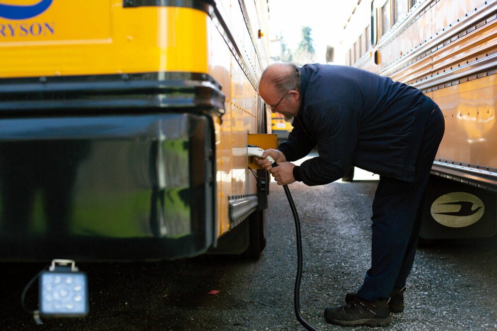 Snohomish School District’s Clayton Lovell plugs in the district’s electric bus after morning routes on Thursday, March 7, 2024, at the district bus depot in Snohomish, Washington. (Ryan Berry / The Herald)
