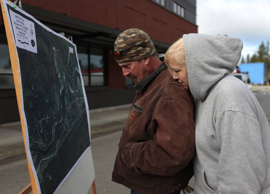 Paul and Keenan Kimball pause to look at the map of the mudslide area outside of the Arlington City Hall on March 23, 2014, in Arlington, Washington. (Mark Mulligan / The Herald)
